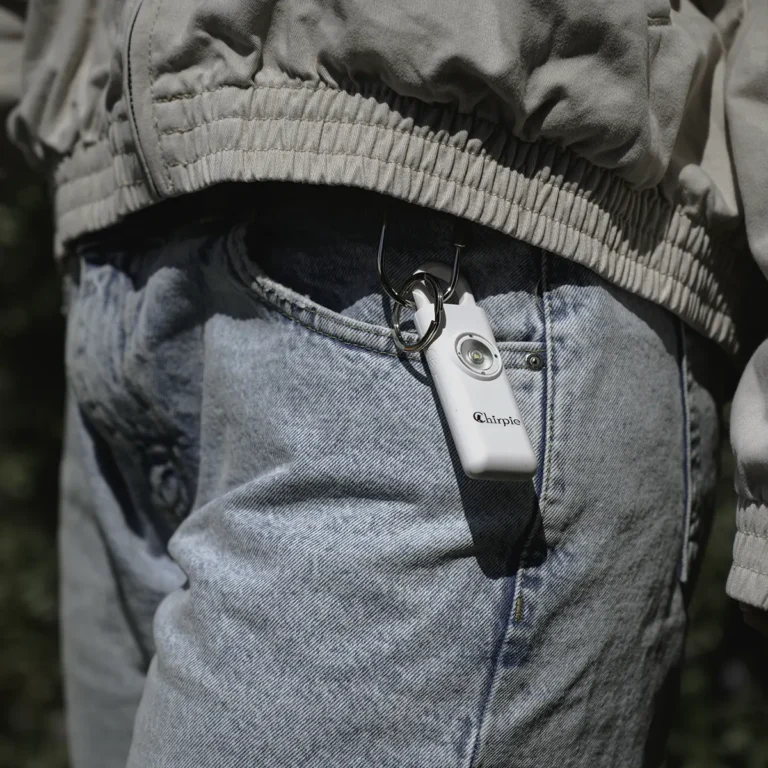 White Chirpie personal safety alarm clipped to belt loop on jeans