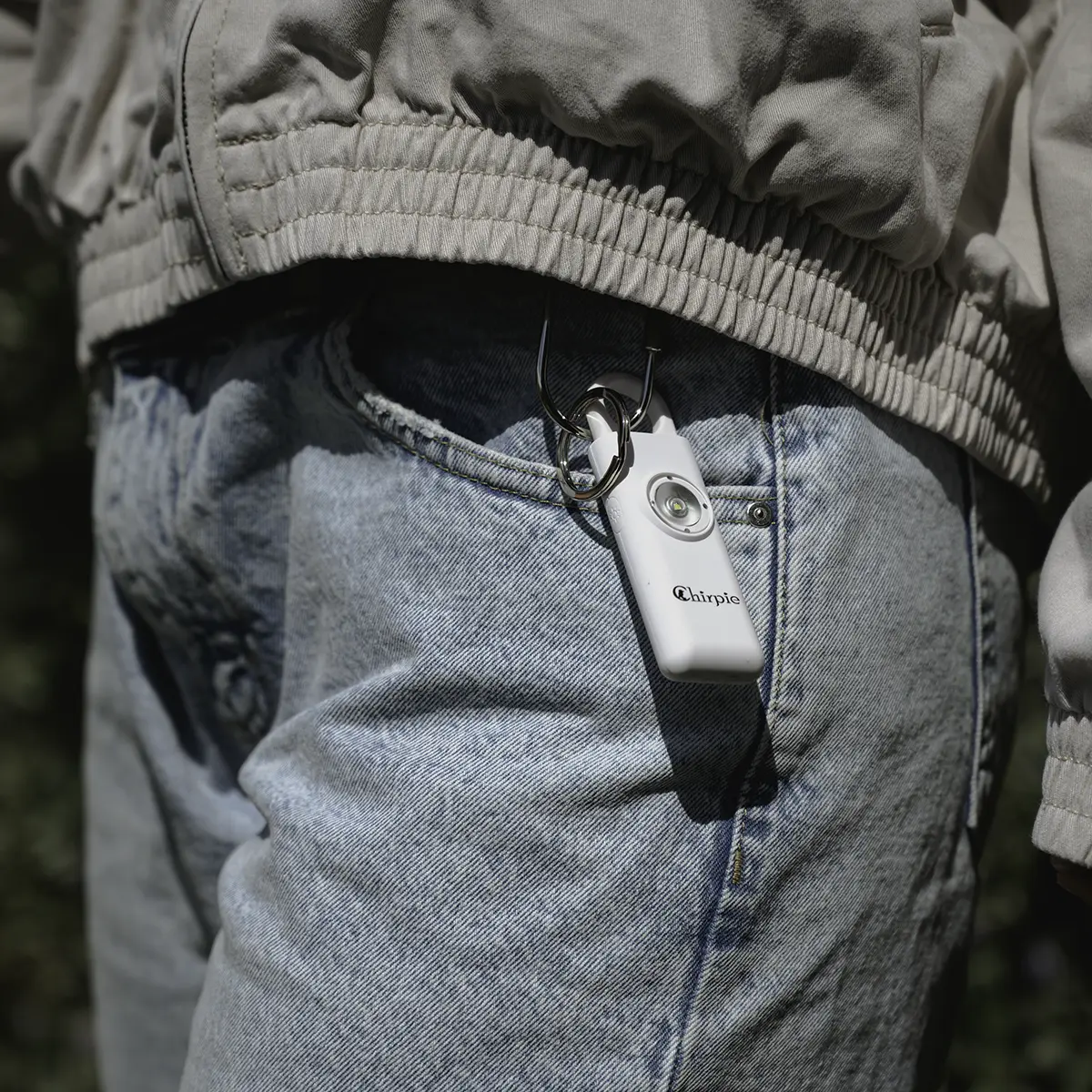 White Chirpie personal safety alarm clipped to belt loop on jeans